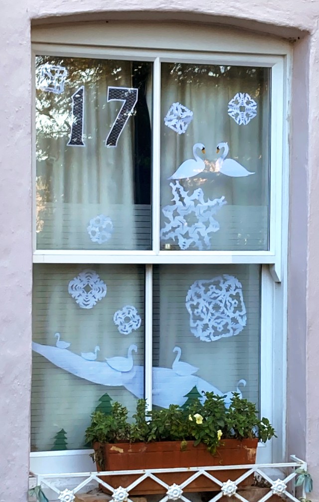 Window with decoration of seven swans cut from white paper