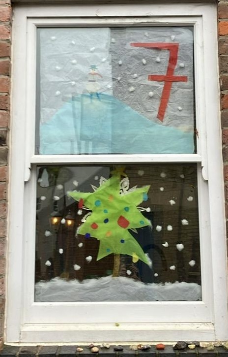 Window with number 7 and scene of snow, clouds and tree