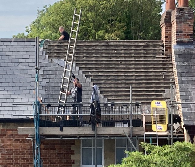 Two men working on slate roof of house
